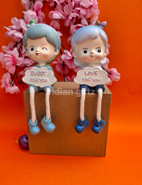 Cute Boy & Girl Love Sharing Hanging Legs Dolls – Polyresin Decorative Showpiece suitable for Tabletop Decoration Gifting, Home Decor, Table, Office Table