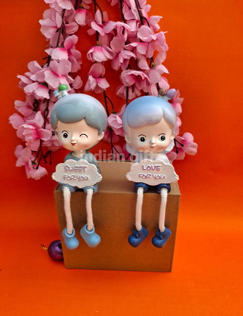 Cute Boy & Girl Love Sharing Hanging Legs Dolls – Polyresin Decorative Showpiece suitable for Tabletop Decoration Gifting, Home Decor, Table, Office Table